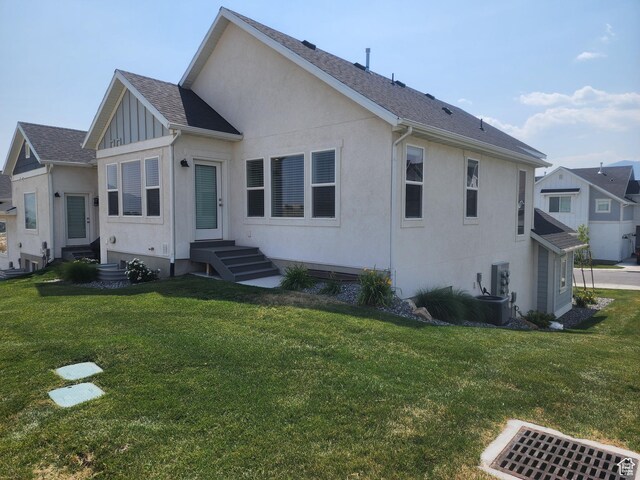9786 N Aaron Ave E Unit 221, Eagle Mountain, UT 84005 - back of house featuring roof with shingles, stucco siding, board and batten siding, entry steps, and a yard