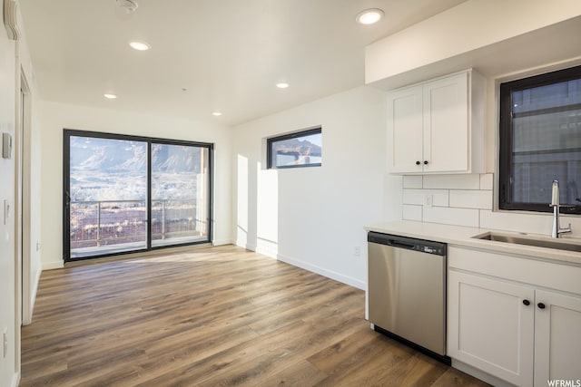kitchen featuring sink, white cabinetry, wood-type flooring, dishwasher, and decorative backsplash
