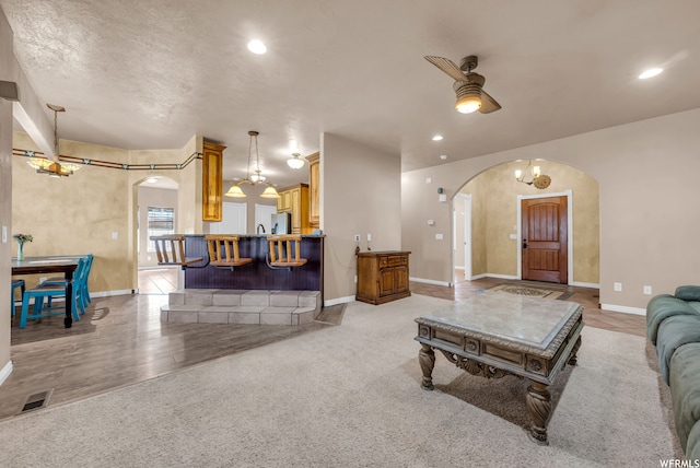 carpeted living room with ceiling fan with notable chandelier