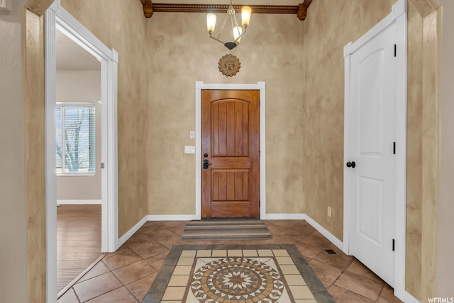 tiled foyer with a chandelier and crown molding