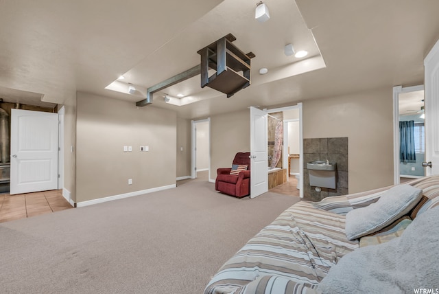 bedroom featuring a tray ceiling, light colored carpet, and ensuite bath