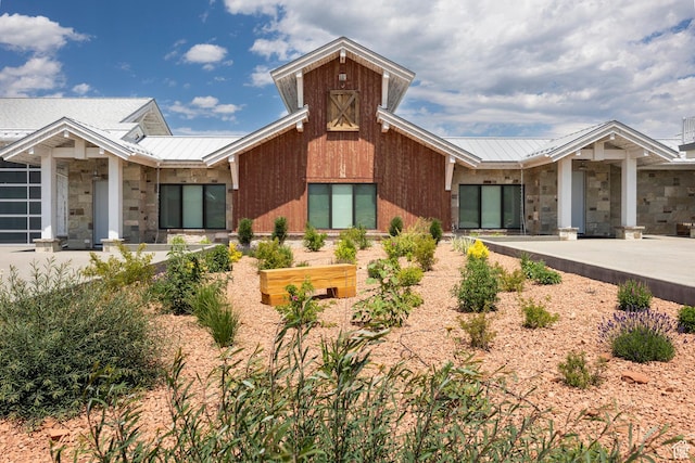 view of front facade with stone siding, metal roof, and a standing seam roof