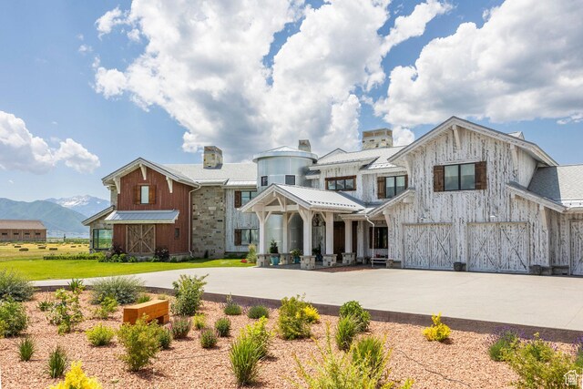 view of front of property featuring an attached garage, driveway, a mountain view, board and batten siding, and a chimney