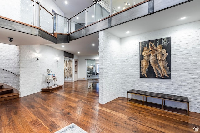 living area with a high ceiling, hardwood / wood-style floors, stairway, and recessed lighting
