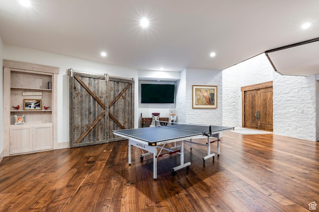 rec room featuring a barn door, wood finished floors, built in shelves, and recessed lighting