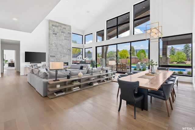 dining room featuring high vaulted ceiling, a chandelier, and light wood-type flooring