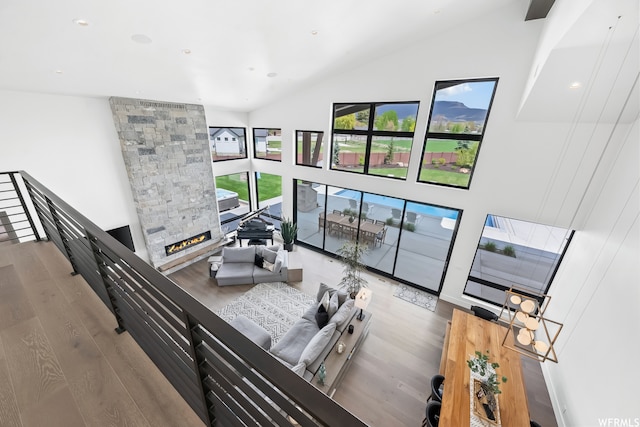 living room featuring high vaulted ceiling, a stone fireplace, and hardwood / wood-style flooring
