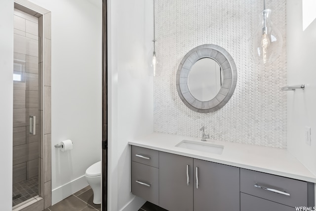 bathroom featuring toilet, tile floors, a shower with shower door, and vanity