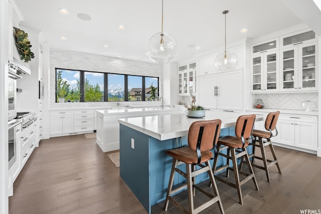 kitchen featuring hanging light fixtures, white cabinetry, dark hardwood / wood-style floors, a kitchen breakfast bar, and a center island