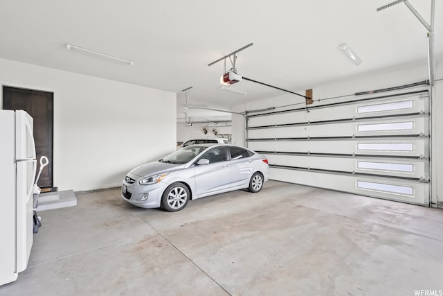 garage with a garage door opener and white fridge