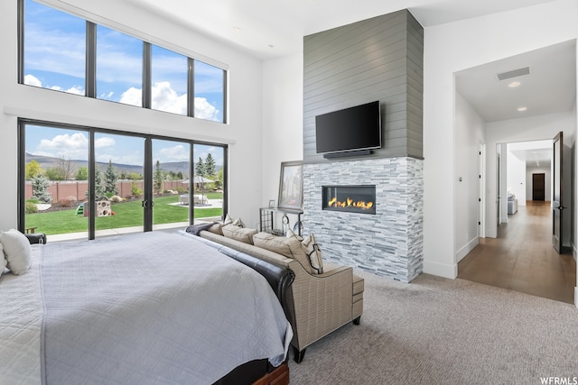 bedroom featuring light hardwood / wood-style flooring, a fireplace, and a high ceiling