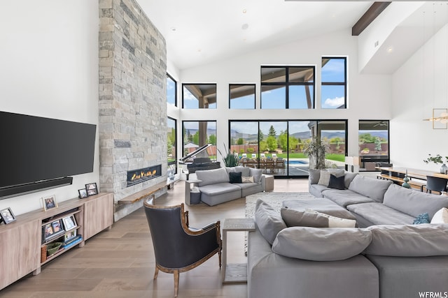 living room featuring a stone fireplace, hardwood / wood-style floors, high vaulted ceiling, and beamed ceiling