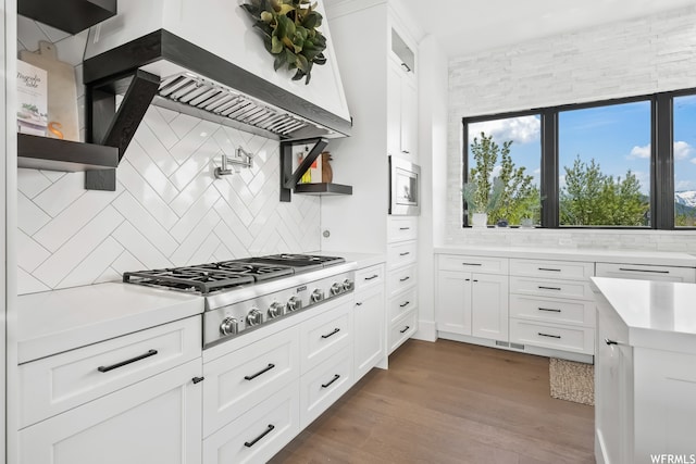 kitchen with tasteful backsplash, stainless steel appliances, white cabinets, and dark wood-type flooring
