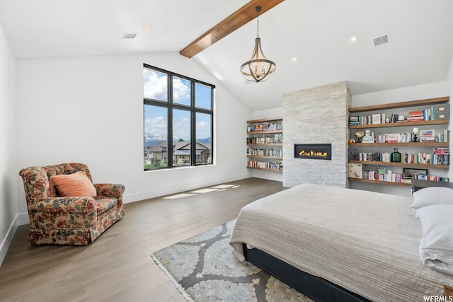 bedroom with multiple windows, an inviting chandelier, light hardwood / wood-style flooring, and a stone fireplace