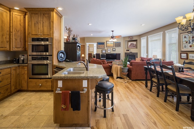 487 Kiva Dr, Moab, UT 84532 - kitchen featuring light tile floors, a breakfast bar, ceiling fan with notable chandelier, stainless steel double oven, and sink