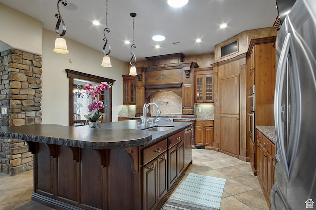 kitchen with appliances with stainless steel finishes, tasteful backsplash, an island with sink, decorative light fixtures, and sink