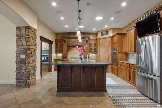 kitchen featuring an island with sink, decorative light fixtures, sink, appliances with stainless steel finishes, and decorative backsplash