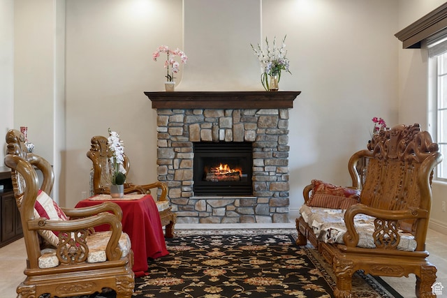 sitting room featuring a stone fireplace and light colored carpet