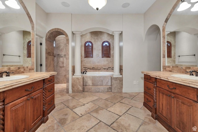 bathroom featuring ornate columns, vanity, and tiled tub