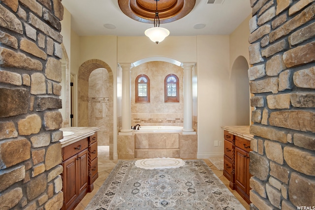 bathroom featuring tiled bath, a tray ceiling, ornate columns, and vanity