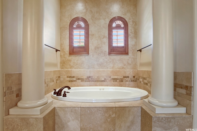 bathroom with ornate columns and tiled tub