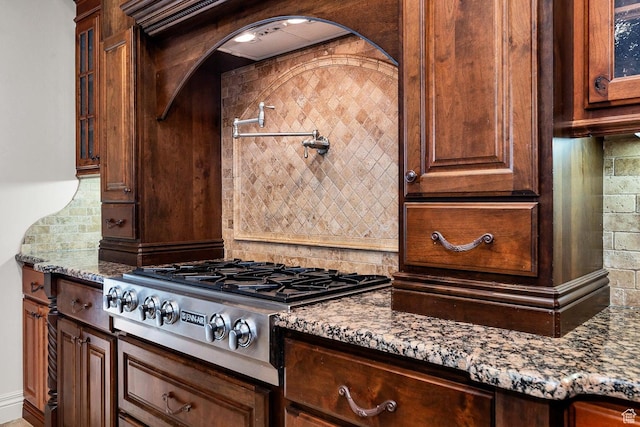 kitchen with decorative backsplash, dark stone counters, and stainless steel gas stovetop