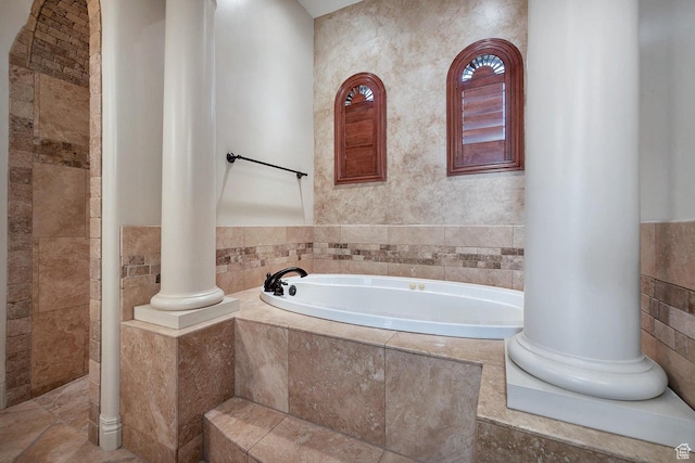 bathroom with decorative columns, tile walls, and tiled tub
