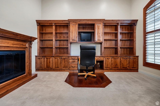 office space with light carpet, built in desk, and plenty of natural light