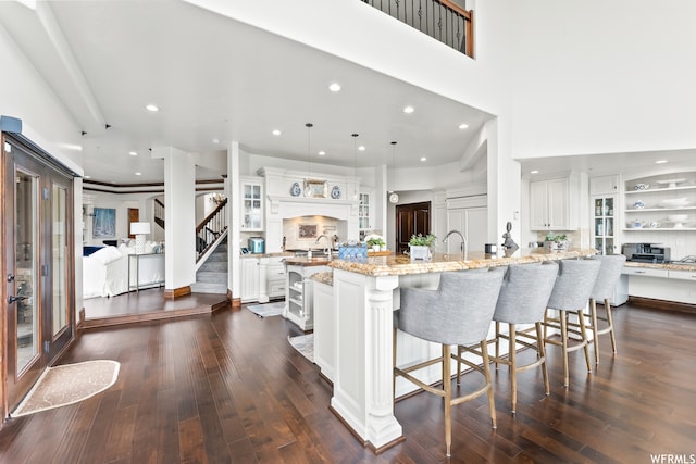 4159 Moose Hollow Rd, Park City, UT 84098 - kitchen featuring pendant lighting, light stone counters, an island with sink, a kitchen bar, and white cabinets