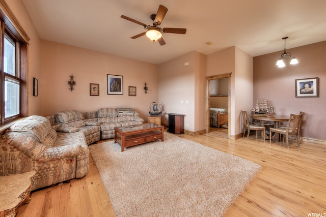 living room with light hardwood / wood-style floors and ceiling fan with notable chandelier