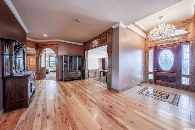 entrance foyer with light hardwood / wood-style floors, ornamental molding, a healthy amount of sunlight, and a chandelier