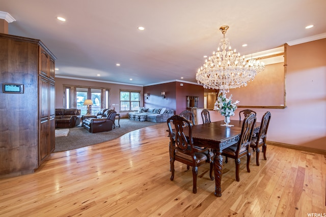 dining area with ornamental molding, a notable chandelier, and light wood-type flooring