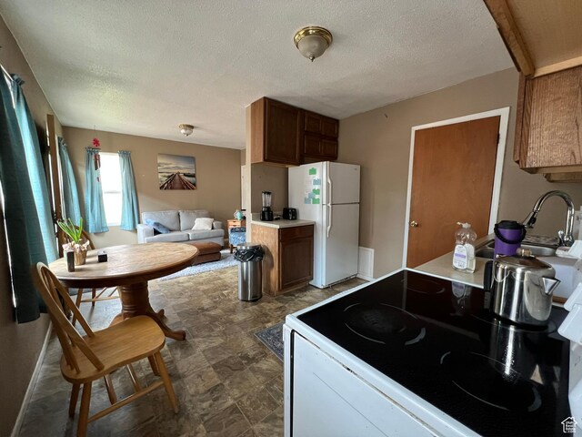 195 E 200 N, Moab, UT 84532 - kitchen with freestanding refrigerator, stove, a textured ceiling, stone finish floors, and light countertops