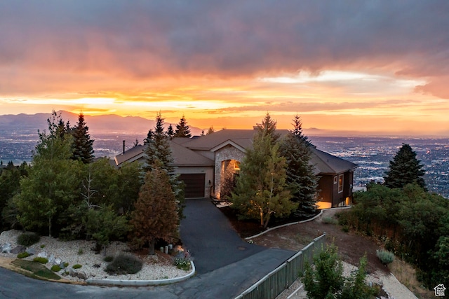 view of property hidden behind natural elements featuring a mountain view and a garage