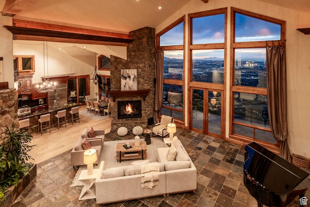 living room with hardwood / wood-style floors, a stone fireplace, vaulted ceiling with beams, and a chandelier