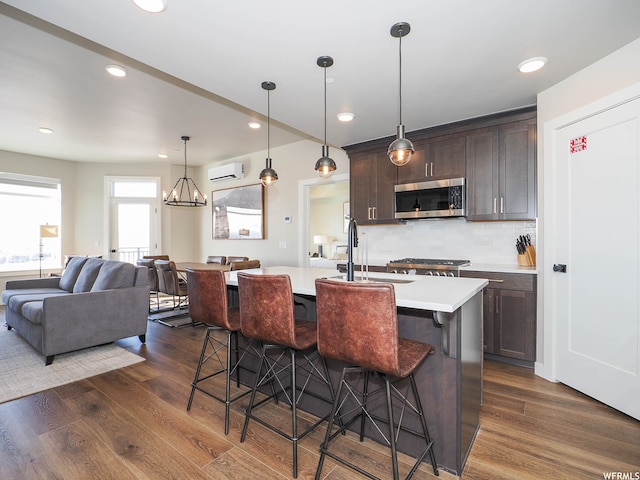 909 W Peace Tree Trl Unit 601, Heber City, UT 84032 - kitchen featuring dark wood-style floors, a breakfast bar area, stainless steel microwave, dark brown cabinets, and a wall mounted air conditioner