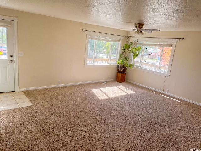 carpeted empty room with ceiling fan, plenty of natural light, and a textured ceiling