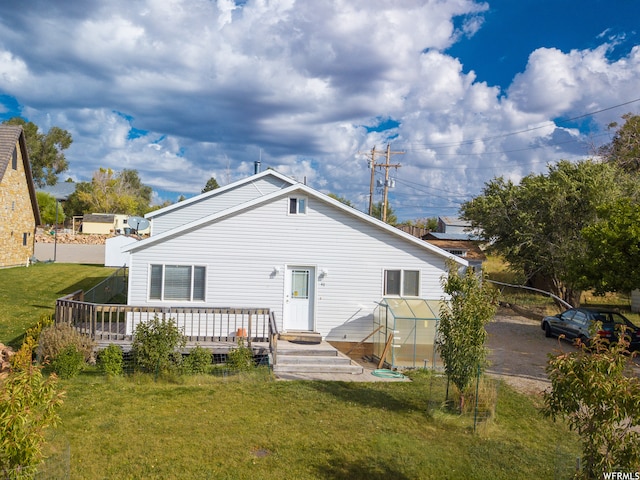 back of property featuring a deck and a lawn