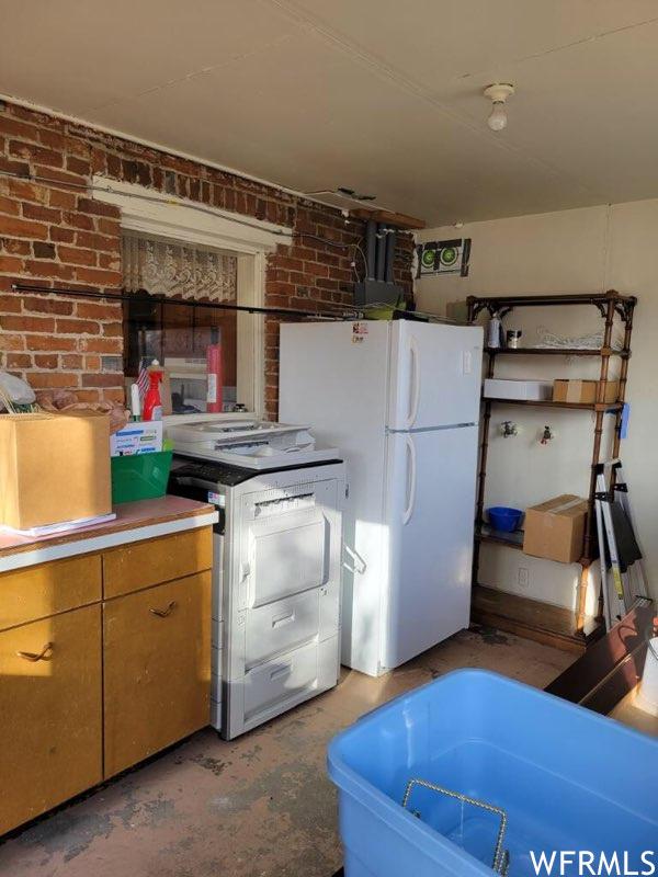 506 E Main St, Midway, UT 84049 - kitchen with range, freestanding refrigerator, brick wall, and brown cabinetry