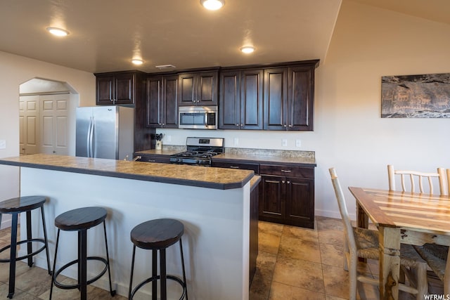 3862 Desert Willow Cir Unit 9-A1, Moab, UT 84532 - kitchen featuring a breakfast bar area, dark brown cabinetry, a kitchen island, and appliances with stainless steel finishes