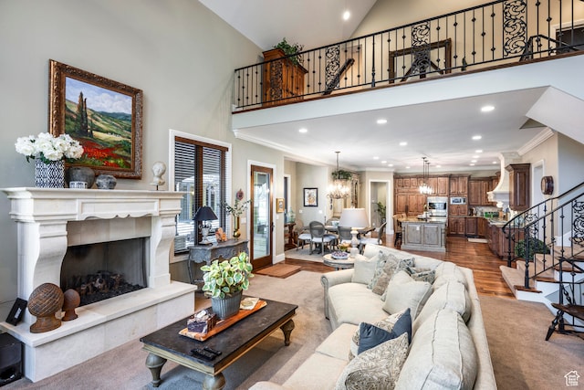 3626 E Granite Bench Ln S, Sandy, UT 84092 - living room featuring a towering ceiling, ornamental molding, a chandelier, a tiled fireplace, and light wood-type flooring