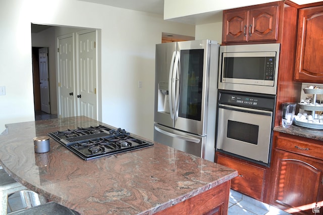 1605 Foxmore St, Pocatello, ID 83204 - kitchen featuring stainless steel appliances, light tile floors, dark stone countertops, and a breakfast bar