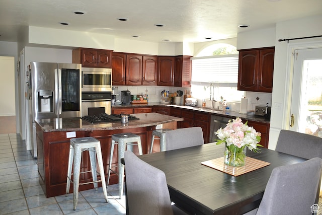 1605 Foxmore St, Pocatello, ID 83204 - kitchen with a center island, light tile flooring, tasteful backsplash, appliances with stainless steel finishes, and sink