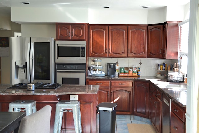 1605 Foxmore St, Pocatello, ID 83204 - kitchen featuring tasteful backsplash, dark tile flooring, a breakfast bar area, appliances with stainless steel finishes, and dark stone countertops