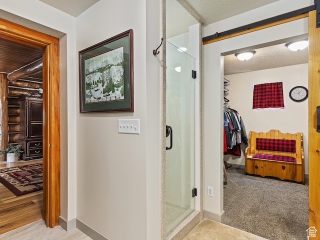 bathroom with an enclosed shower, hardwood / wood-style floors, and a textured ceiling