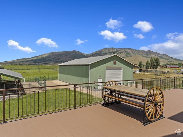 wooden terrace with an outdoor structure, a mountain view, a garage, and a yard