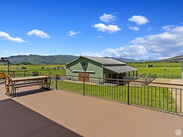 wooden terrace with a rural view, a yard, and a mountain view