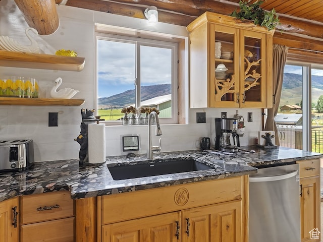 kitchen featuring dark stone counters, a mountain view, dishwasher, and sink