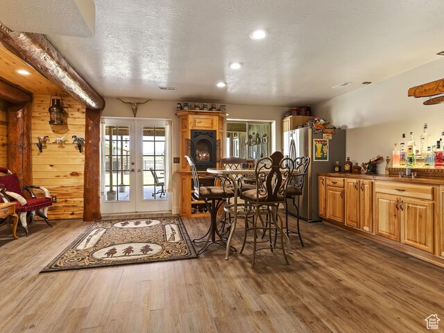 dining area featuring a textured ceiling, wood walls, hardwood / wood-style flooring, and french doors