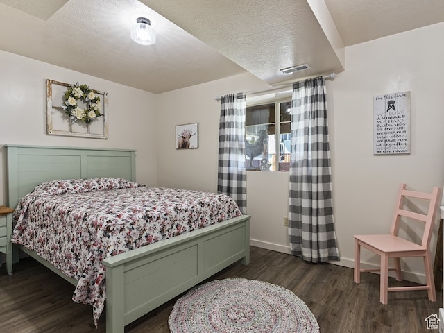 bedroom featuring a textured ceiling and dark hardwood / wood-style flooring